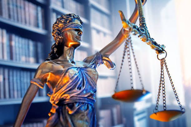 Lady Justice holding balanced scales in a law library